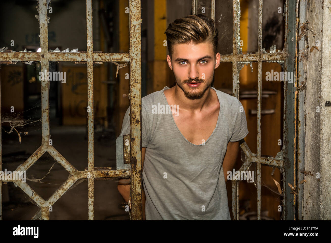 Hübscher blonder junger Mann alte Tür lädt Betrachter eingeben Stockfoto