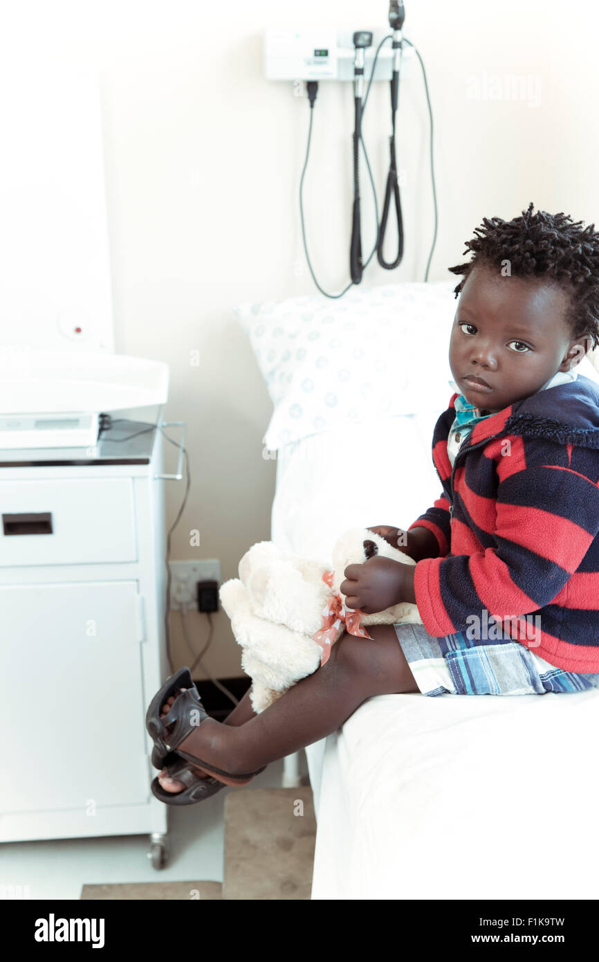 Männliche afrikanische Kind sitzt in einer Klinik-Gemeinde, Blick in die Kamera Stockfoto