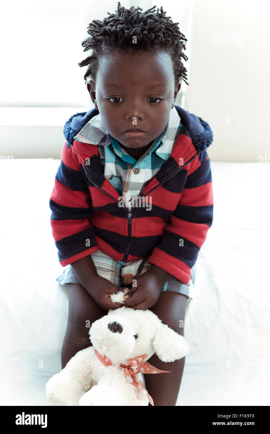 Männliche afrikanische Kind sitzt in einer Klinik-Gemeinde schauen traurig Stockfoto