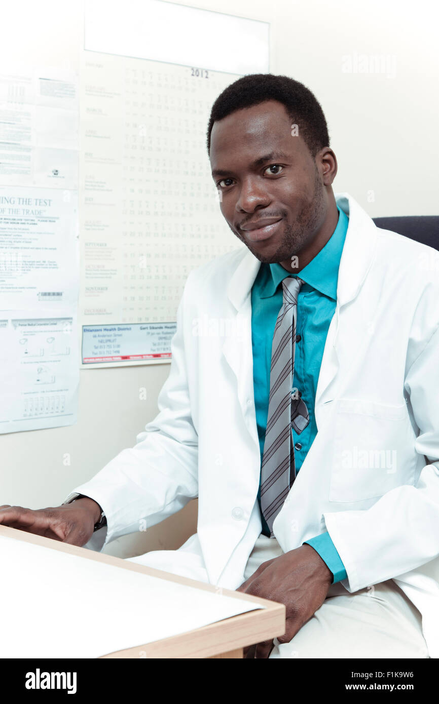 Afrikanische männlichen Arzt sitzt am Schreibtisch, in die Kamera Lächeln Stockfoto
