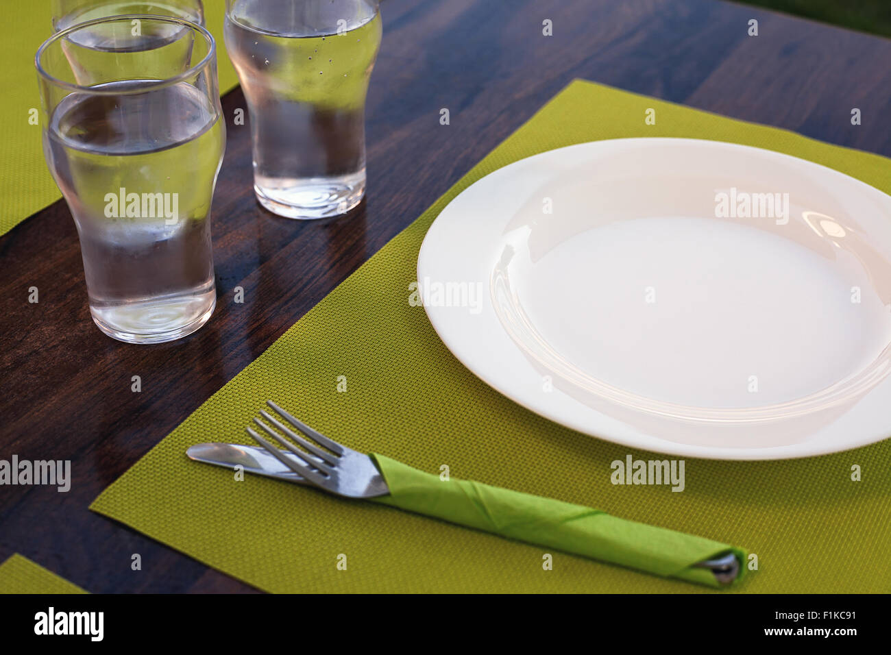 Leeren Sie Mittagszeit, Tisch für das Mittagessen vorbereitet, weißen Teller und Gläser Wasser. Stockfoto