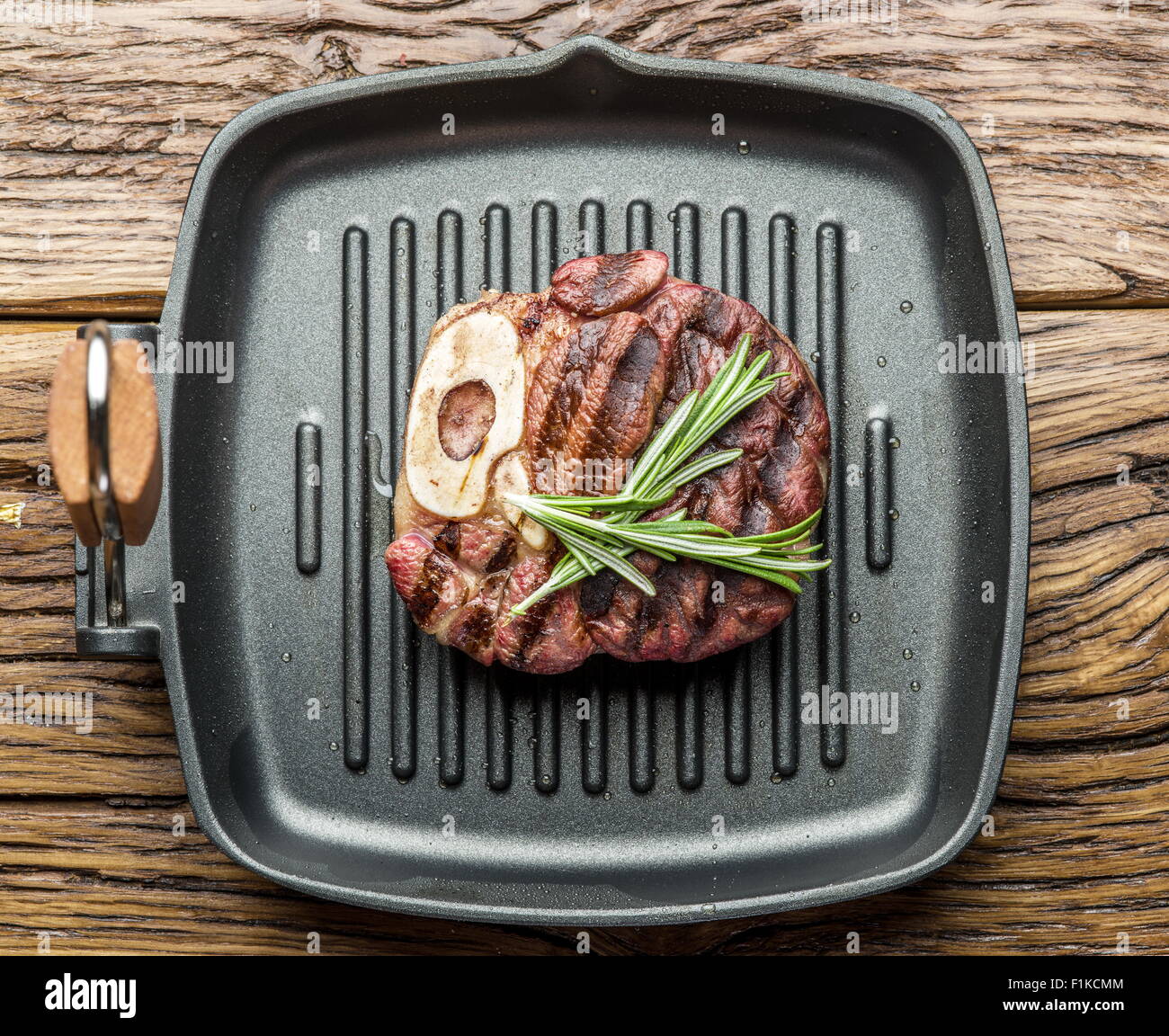 Rindersteak mit Gewürzen auf Pfanne auf Holztisch. Stockfoto