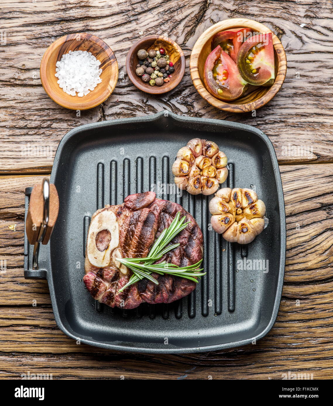 Rindersteak mit Gewürzen auf Pfanne auf Holztisch. Stockfoto