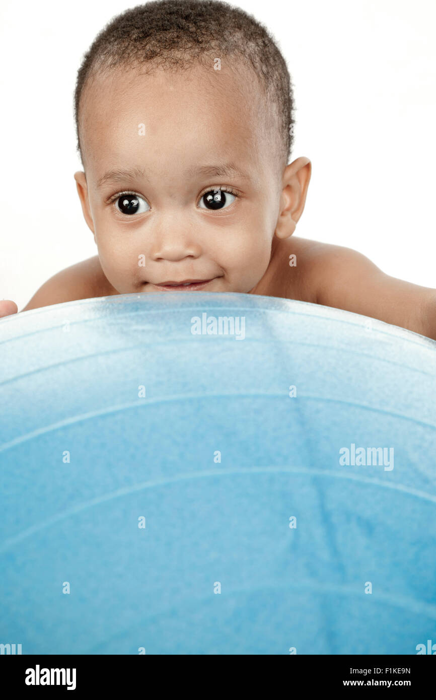 Kind sitzt vor einem weißen Hintergrund mit einem Gymnastikball Stockfoto