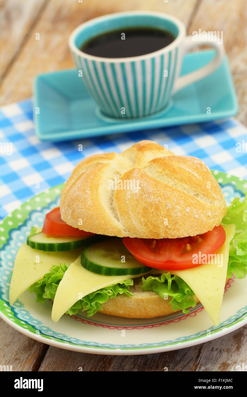 Käse-Brötchen mit Salat, Tomate und Gurke und Tasse Kaffee Stockfoto