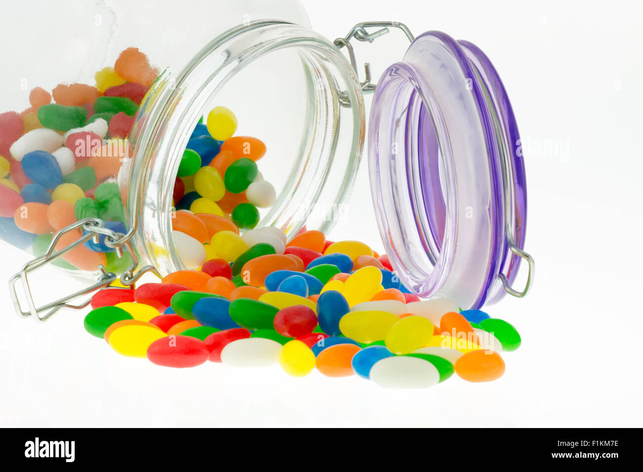 Bunte Jellybean Bonbons aus dem Glas auf weißem Hintergrund Stockfoto