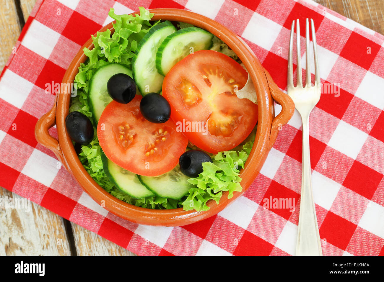 Salat mit Kopfsalat, Tomaten, Gurken und schwarze Oliven in Ton Schüssel Stockfoto