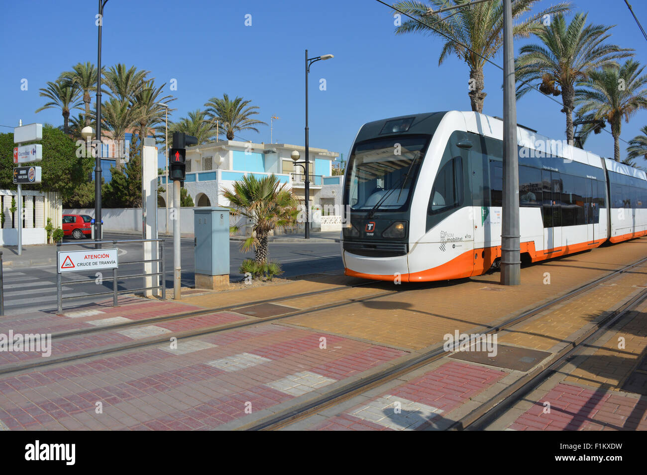 Alicante-Straßenbahn in Campello in Richtung Alicante Stadt reisen. Fußgängerüberweg auf der Straßenbahnlinie mit Rotlicht und Warnung. Stockfoto