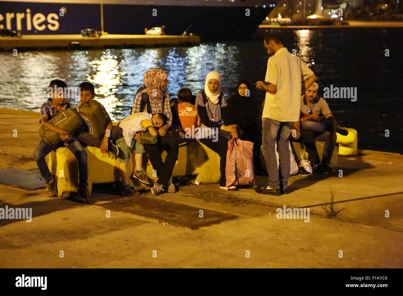 Athen, Griechenland. 3. September 2015. Flüchtlinge sitzen auf einigen Steinen auf den Kais der Hafen von Piräus, wartete auf den Bus zum Bahnhof tragen. Tausende Flüchtlinge angekommen im Hafen von Piräus an Bord der Regierung gecharterten Jet Tera-Fähre von der griechischen Insel Lesbos. Hunderte von Flüchtlingen, vor allem aus Syrien und Afghanistan kommen auf den griechischen Inseln jede Woche hinzufügen bereits Nummer Tausender Flüchtlinge bereits auf den griechischen Inseln. Bildnachweis: Michael Debets/Alamy Live-Nachrichten Stockfoto