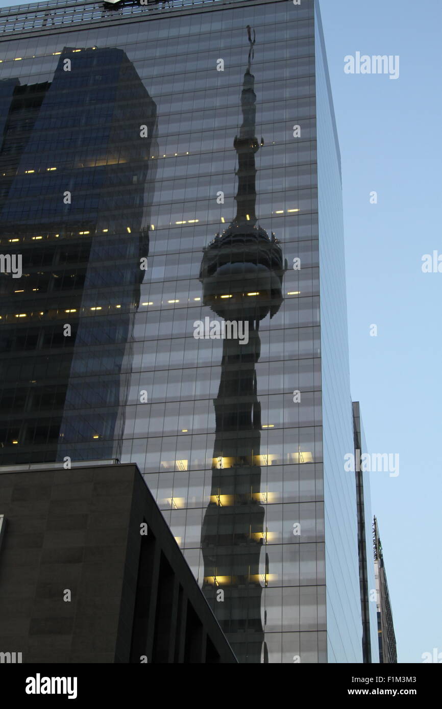 Gespiegelte Ansicht des CN Tower auf Glasbau in Toronto in der Abenddämmerung mit einigen sichtbaren Lichter in den Büros Stockfoto