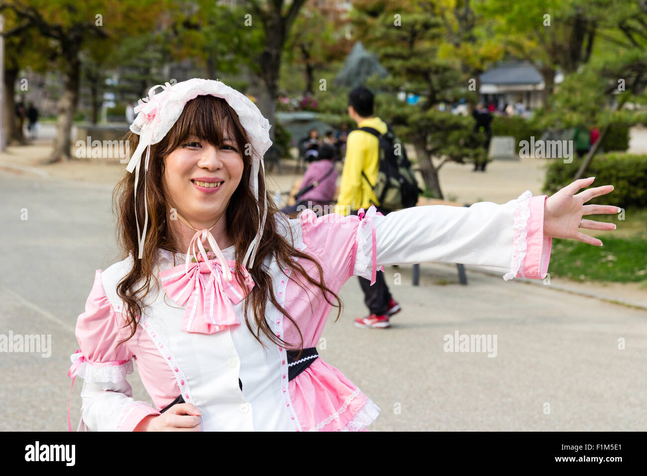 Junge japanische Frauen in Osaka Park gekleidet in Gothic-Lolita rosa und weißen Mädchen Kostüm, schwarze Katze die Socken, für Viewer posieren. Auge - Kontakt. Stockfoto