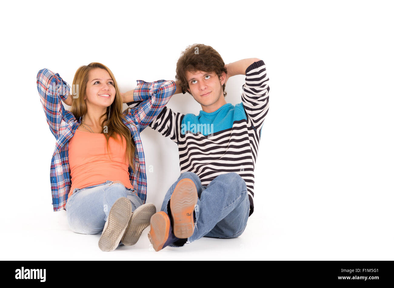 Porträt attraktive junge glückliche Paar in Liebe Mann und Frau in weißem Hintergrund sitzen auf isolierten Boden Nachschlagen von entspannenden Hände hinter ihren Köpfen träumen Stockfoto