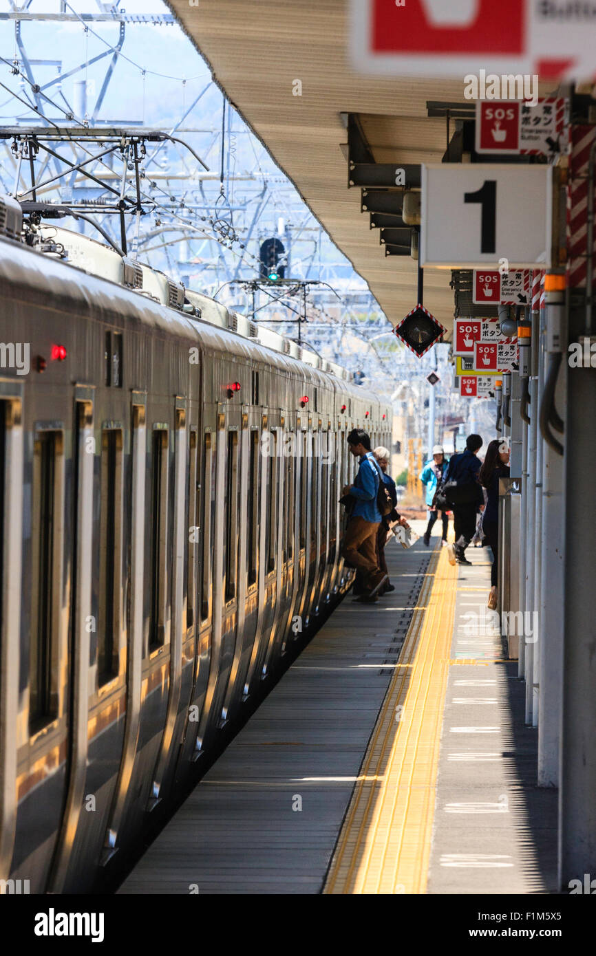 Japan, JR Amagaski, Blick entlang elektrische Triebwagen der S-Bahn auf Gleis 1, wenige Leute einsteigen, aber hauptsächlich leere Plattform. Stockfoto