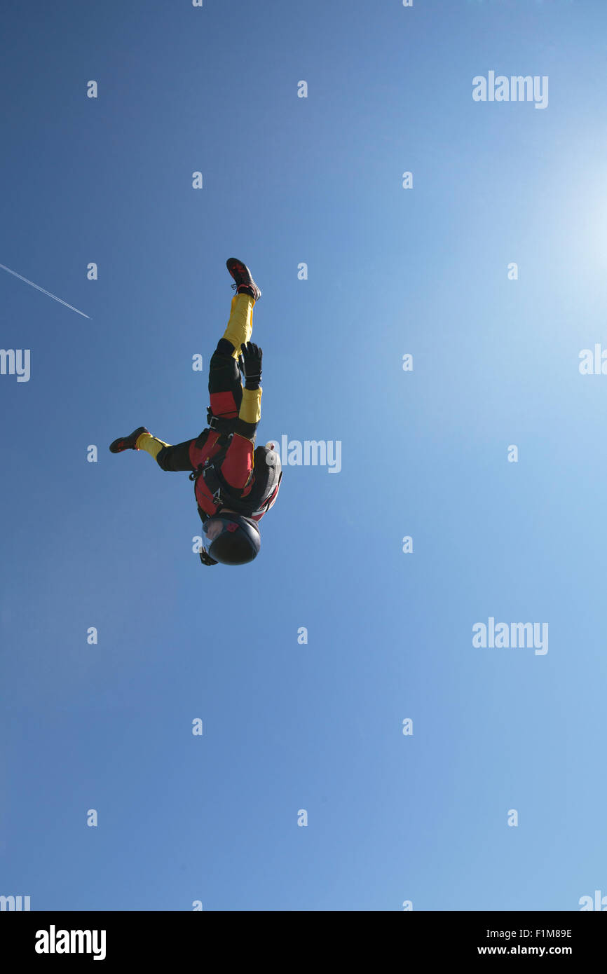 Dieser Fallschirmspringer Mädchen fliegt in einem Kopf nach unten in den blauen Himmel ohne Wolken. Sie ist schnell mit 130 km/h auf dem Kopf fliegen. Stockfoto