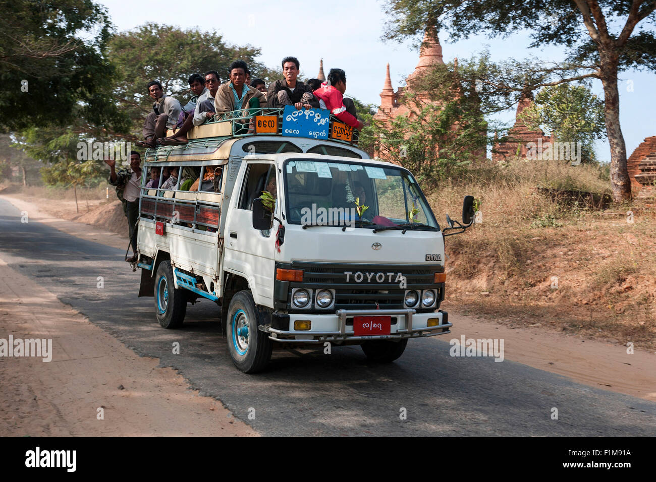 Öffentliche Verkehrsmittel, Kleinbus mit Menschen drin und auf dem Dach fahren auf der Straße, in Bagan, Mandalay Region, Myanmar Stockfoto