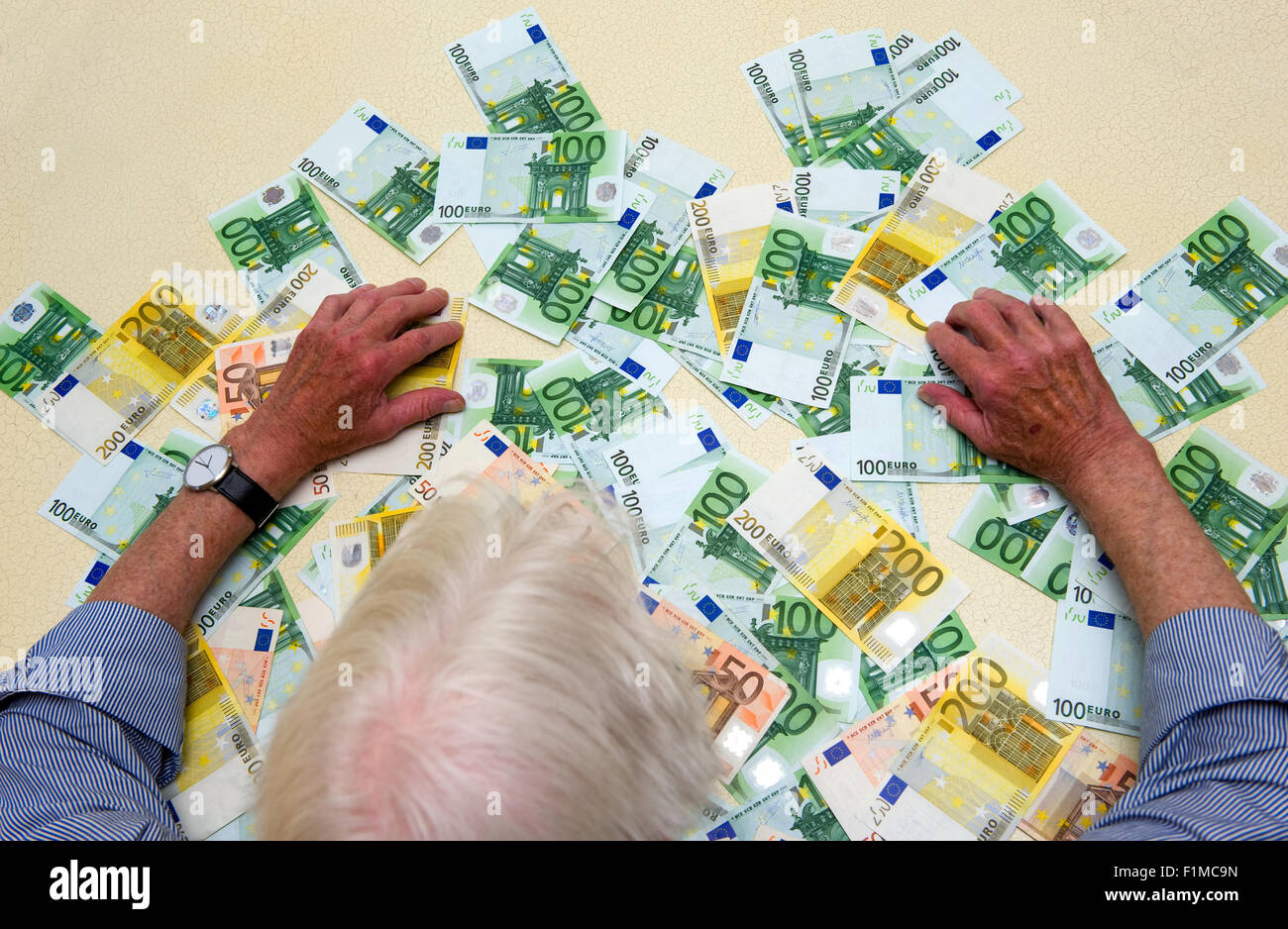 Ein älterer Mann mit einer Menge von Euro-Banknoten auf den Tisch Stockfoto
