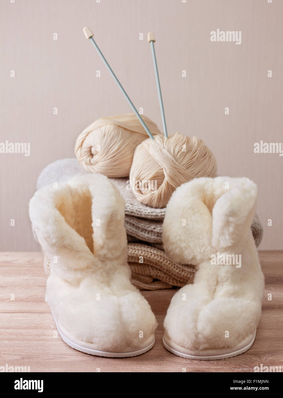 Paar warme Winter Schaffell-Hausschuhe (Alpaka), Wolle, Stricknadel auf  einem Haufen warme wollene Kleidung (Tiefenschärfe Stockfotografie - Alamy