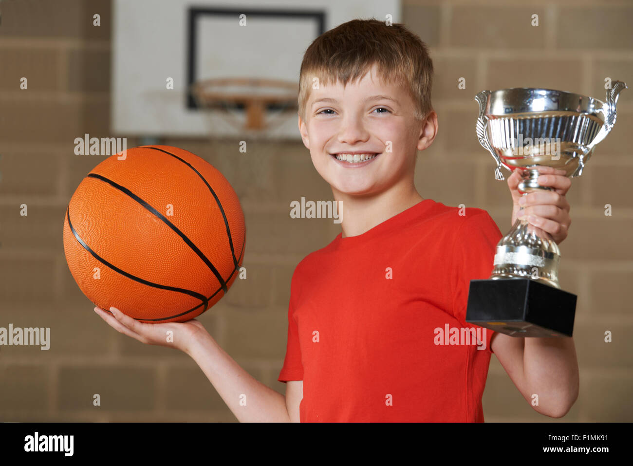 Junge mit Basketball und Trophy In Turnhalle Stockfoto