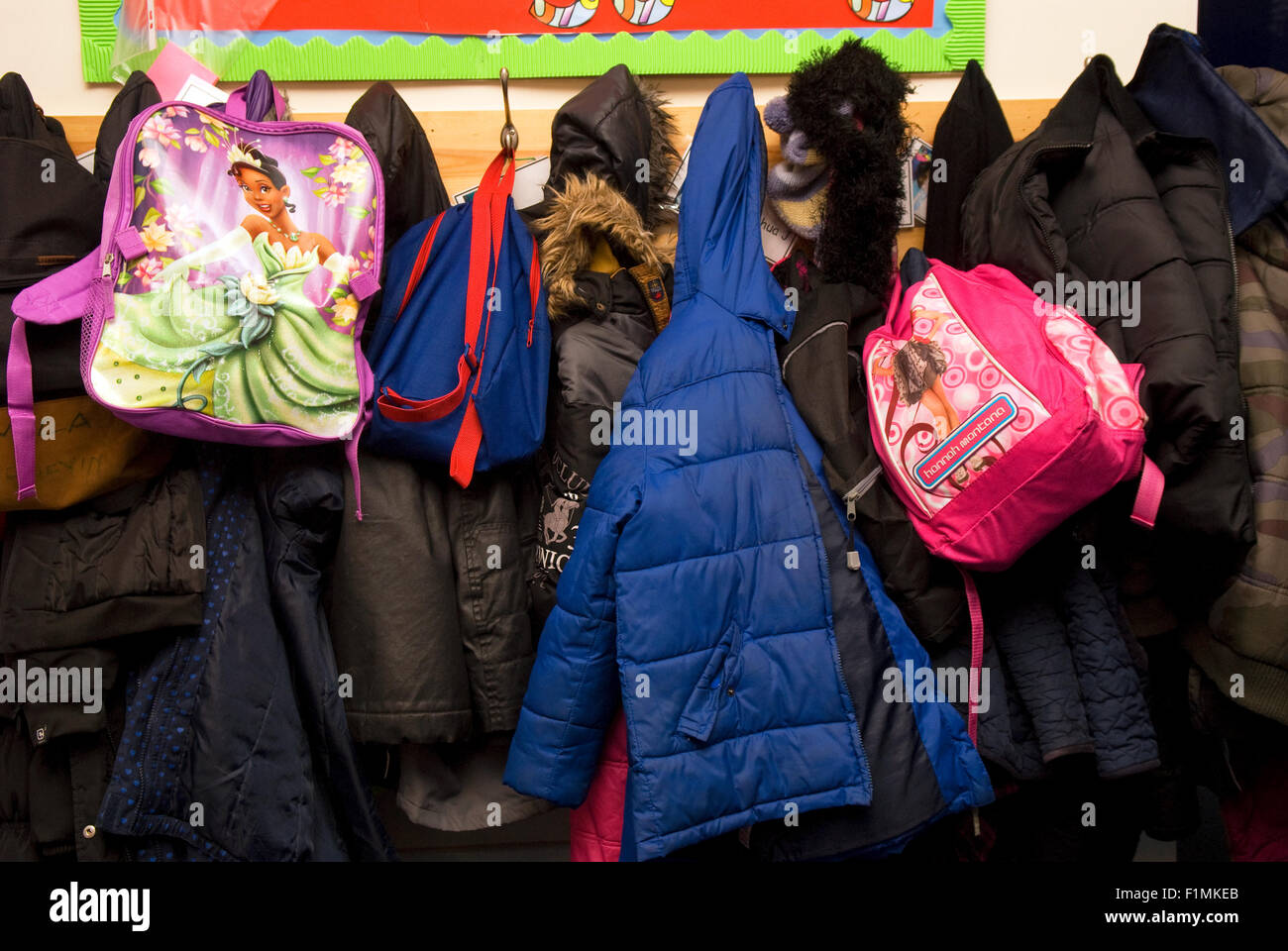 Schüler der Grundschulen Mäntel aufhängen auf Mantel Haken im Flur der Schule, London, UK. Stockfoto