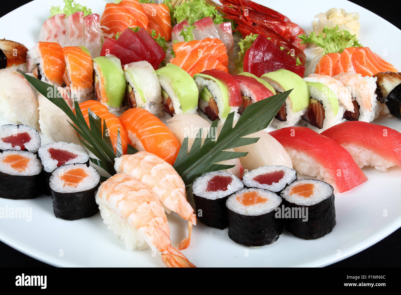 Close-up Sushi und Sashimi auf Runde weiße Platte auf einem schwarzen Hintergrund gemischt Stockfoto