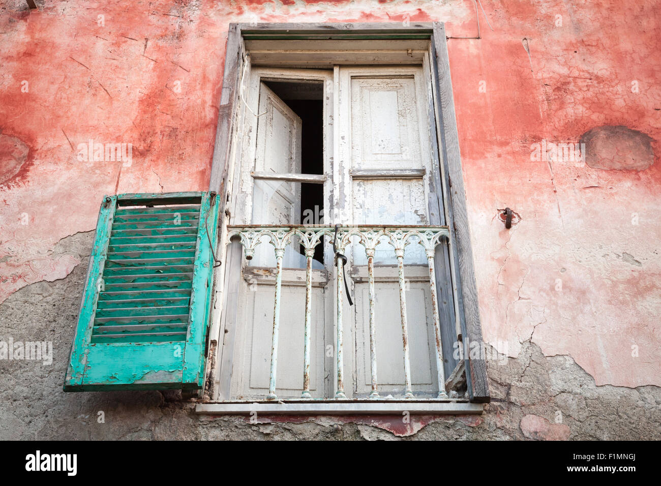 Alte verlassene Hauswand mit weißen hölzernen Balkontür und grünen Fensterläden, Gaeta, Italien Stockfoto