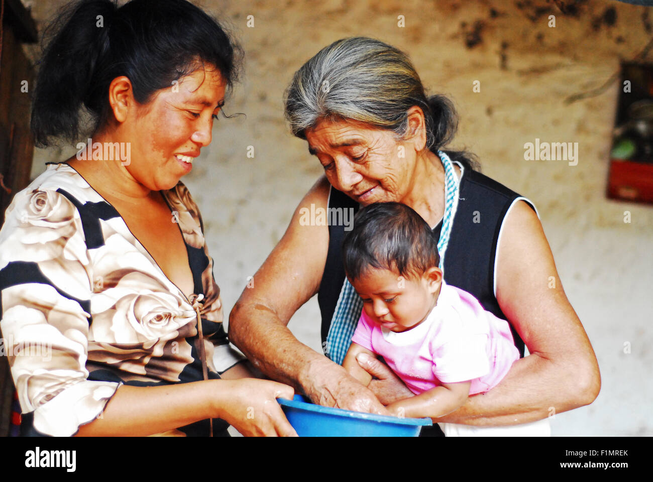 Guatemala, Los Achiotes, Mutter und Großmutter Händewaschen Babys (Gudelia Lopez, 69 Jahre; Ana de Jesus Rodriguez Lopez 35 Jahre und Baby Cristel Yuseth Rodriguez Lopez 9 Monate) Stockfoto