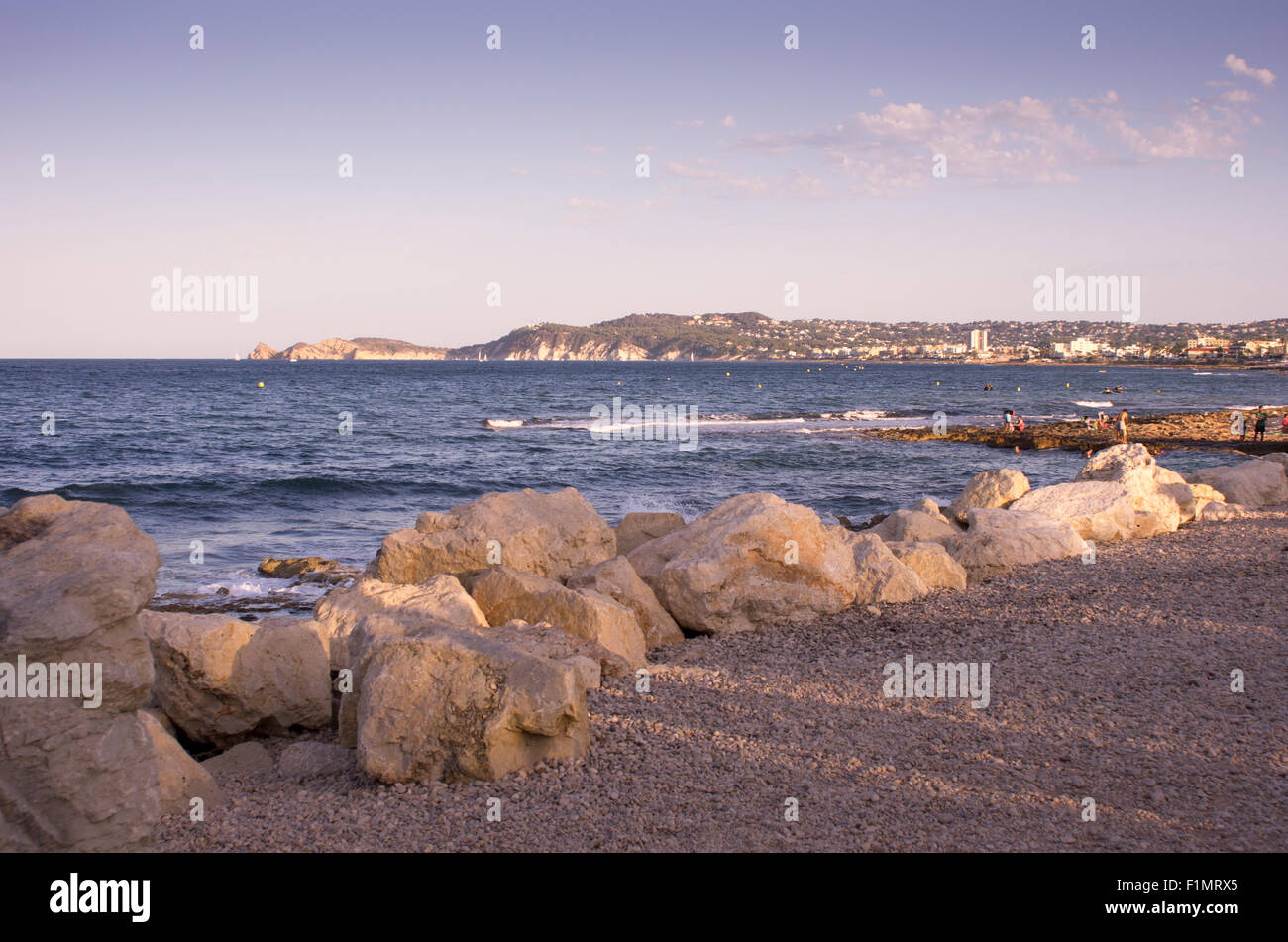 Die Bucht von Javea, Spanien, mit Felsen im Vordergrund und Klippen im Hintergrund Stockfoto