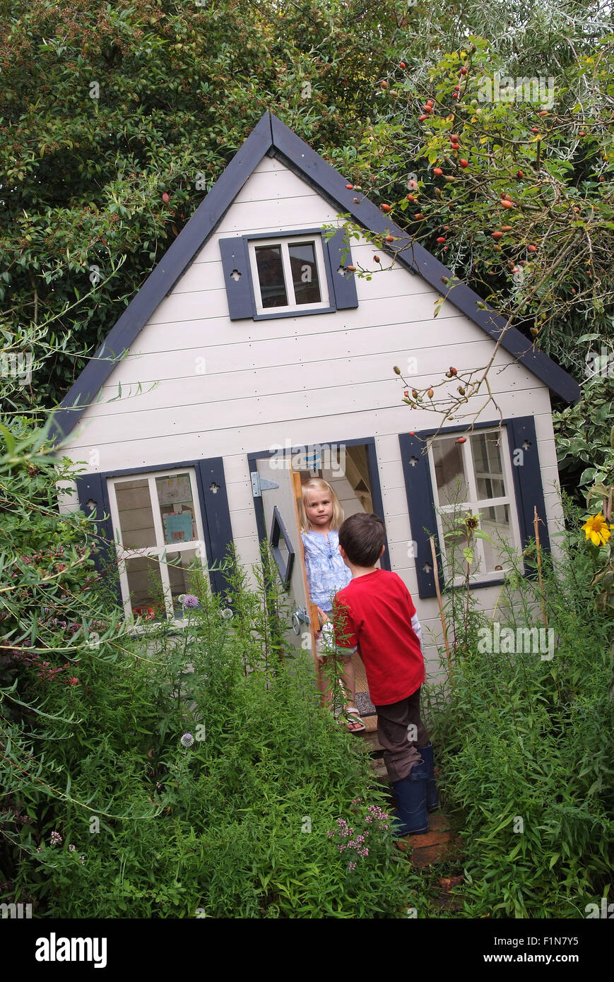 Lucy & Seb Tyler mit ihre kleine hölzerne Garten Spielhaus (Spielhaus) in Wiltshire, England, ein, wo sie spielen mit Spielzeug und Bären. Stockfoto