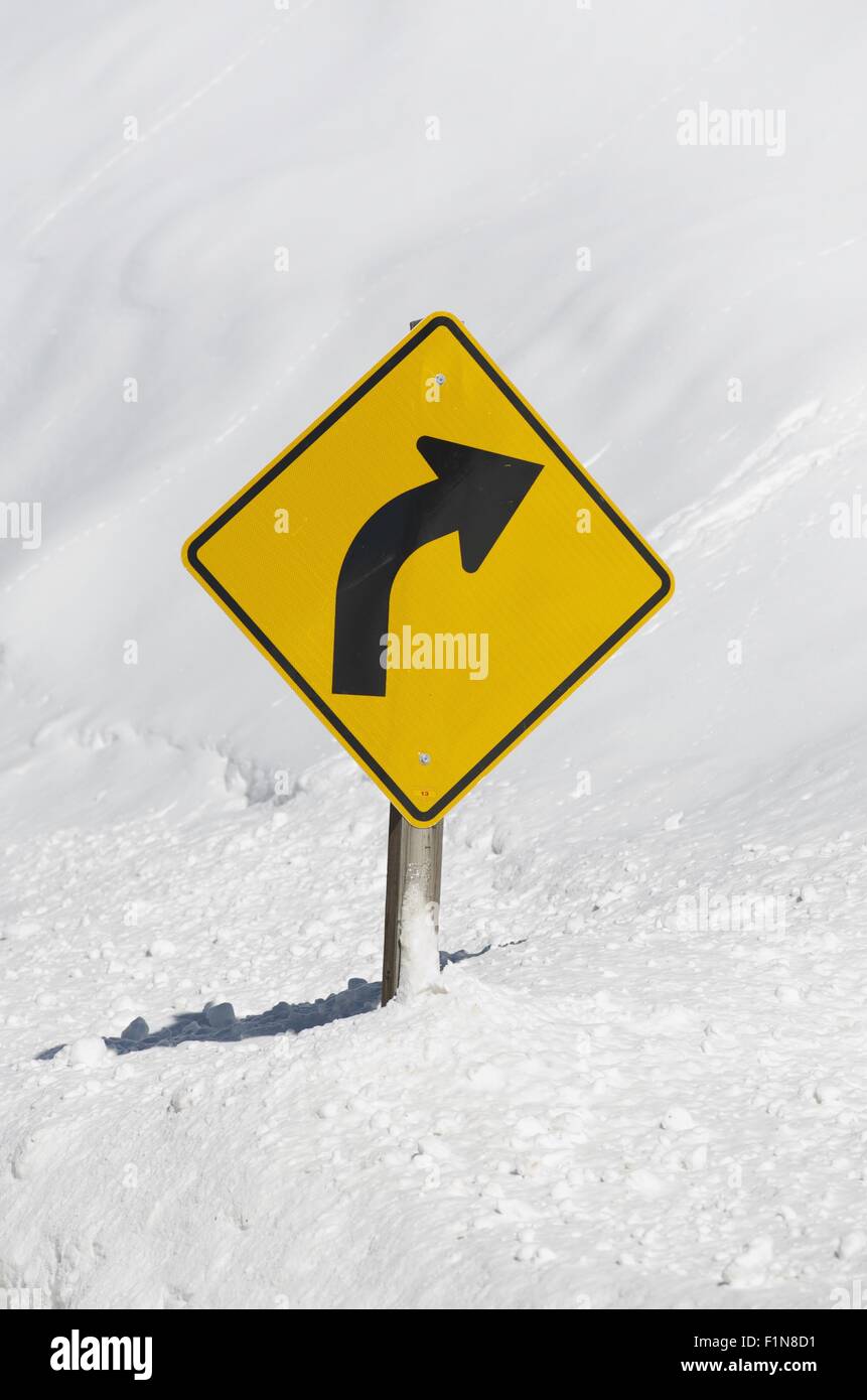 Gebogene Winterdienst. Kurve vor gelben Verkehrszeichen im Schnee. Stockfoto