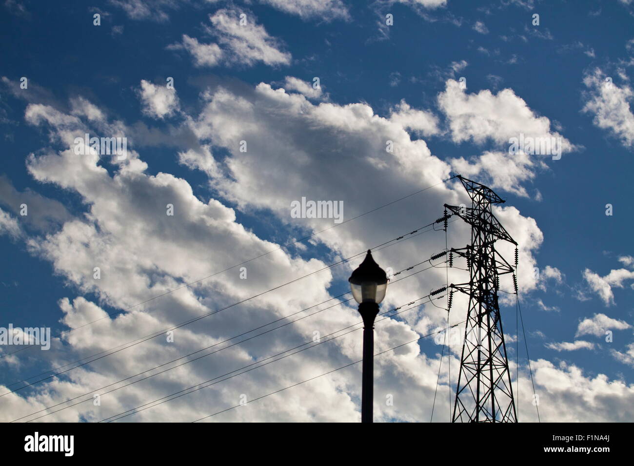 Silhoutted elektrische Hochspannung macht post gegen blauen Wolkenhimmel Stockfoto