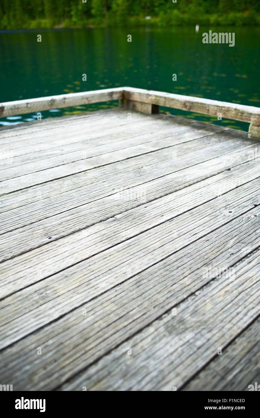 Holz-Dock auf dem See - vertikale Fotografie. Holz-Dock-Ecke. Grün und klaren Wasser des Sees. Stockfoto