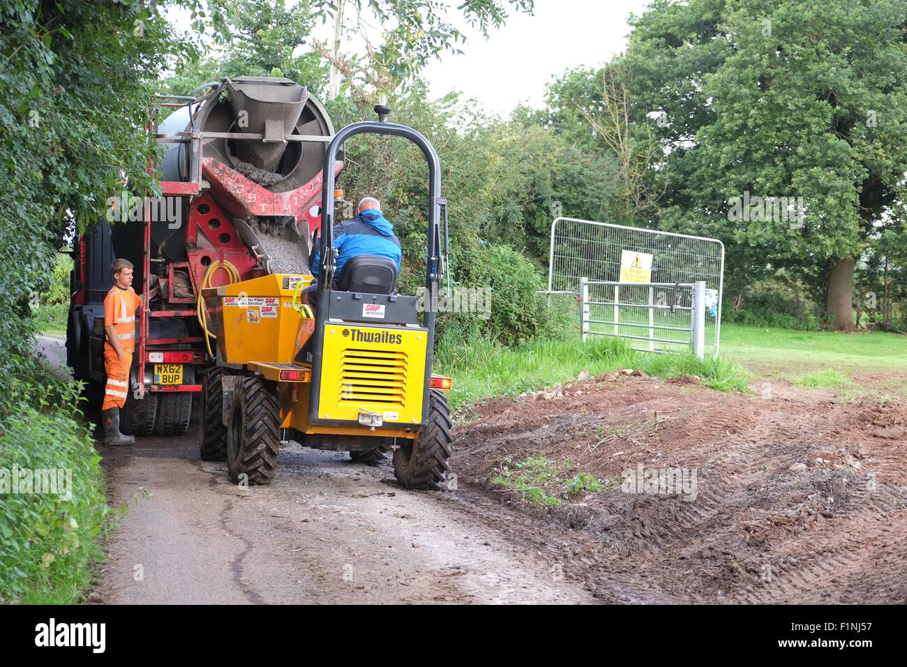 Entladen ein konkreten LKW in einen schmalen Feldweg in einen kleinen Bauherren-Kipper für die Platzierung auf einem Bauernhof Stockfoto