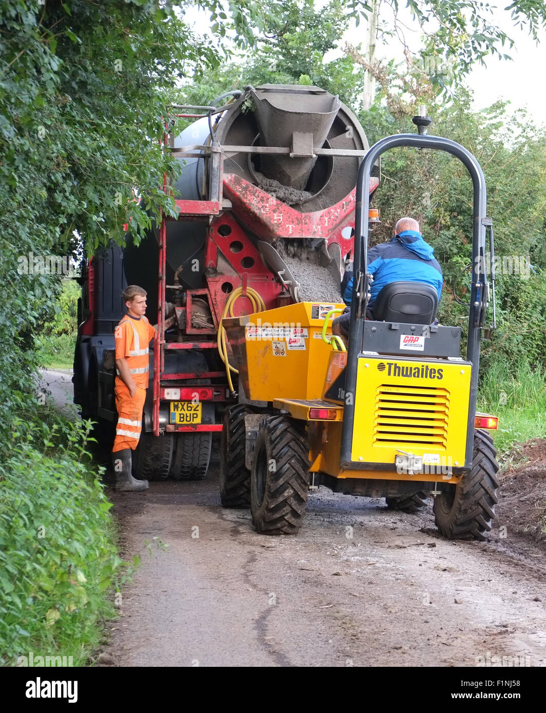 Entladen ein konkreten LKW in einen schmalen Feldweg in einen kleinen Bauherren-Kipper für die Platzierung auf einem Bauernhof Stockfoto