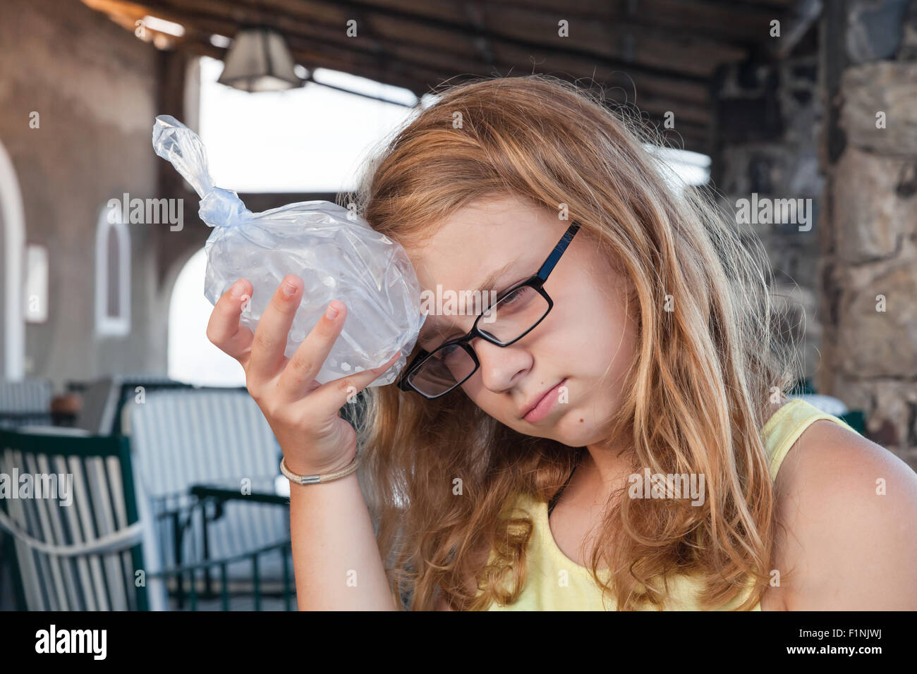 Blonden Mädchens kaukasischen stellt Eis in einem Plastikbeutel auf den Kopf Stockfoto