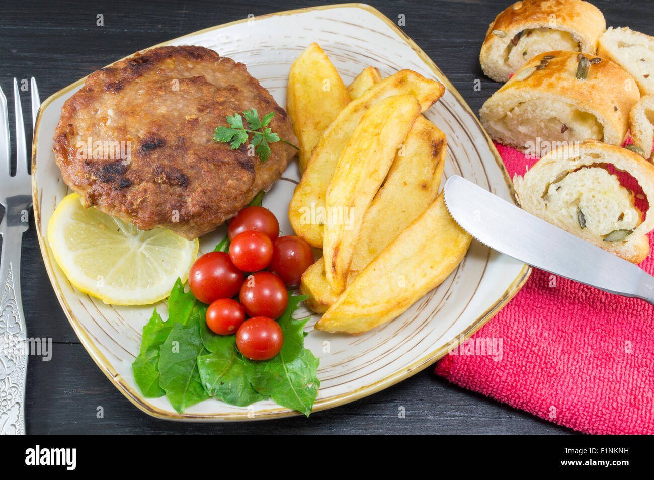 Hamburger-Steak mit Kartoffeln, Tomaten und Oliven Brot auf dem Silbertablett serviert Stockfoto