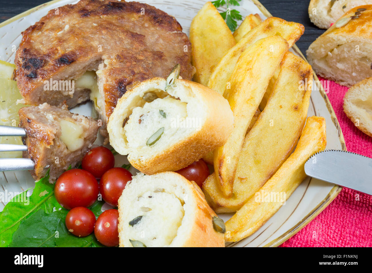 Hamburger-Steak mit Kartoffeln, Tomaten und Oliven Brot auf dem Silbertablett serviert Stockfoto