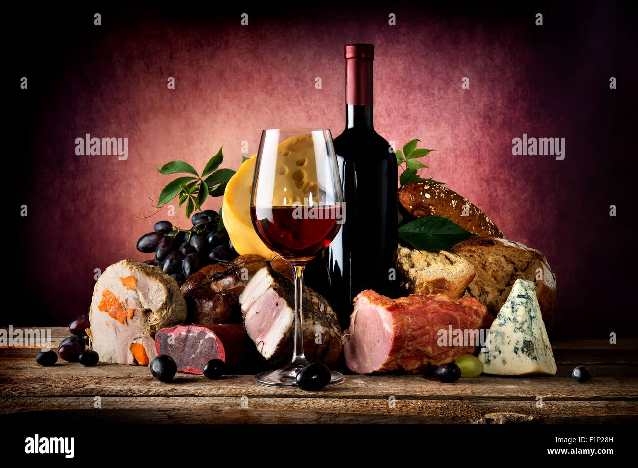 Rotwein und verschiedenen Speisen auf einem Holztisch Stockfoto