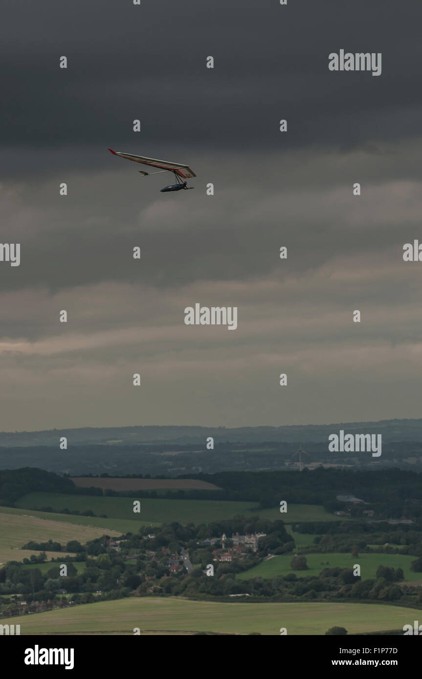 Firle Beacon, East Sussex, Großbritannien. September 2015. Para & Hang Gliders nutzen den Nördlichen Wind in den South Downs. Helle Zaubersprüche zwischen den dunklen Wolken. Stockfoto