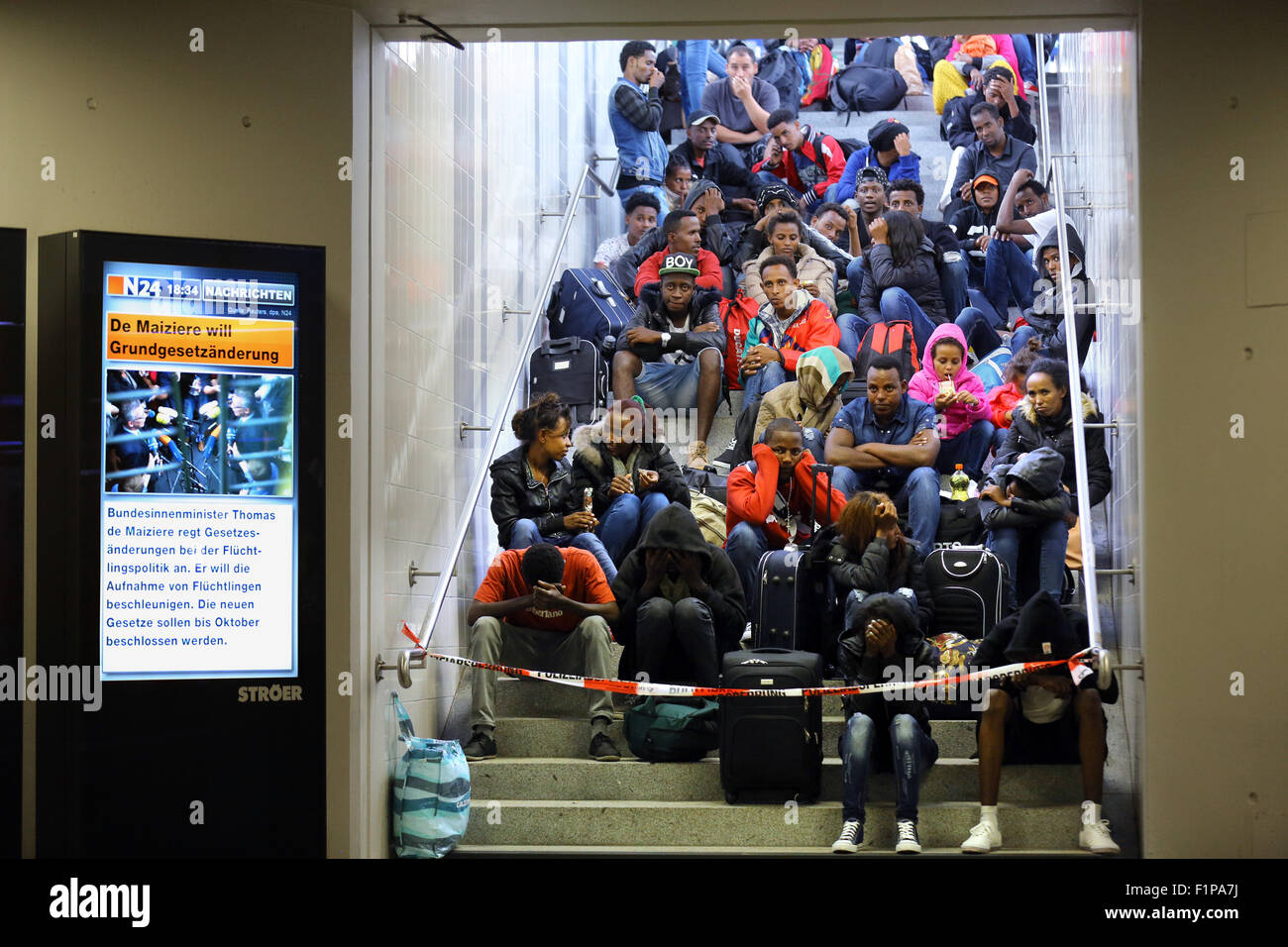 Migranten aus Eritrea kommen mit dem Zug von Verona/Italien am Bahnhof Rosenheim am 2. September. 2015 in Rosenheim, Deutschland. Die elektronischen Nachrichten Plakatwand liest "Deutsche Innenminister will Verfassungsänderung durch Zustrom von Migranten". Tausende von Migranten sind über Libyen, Mittelmeer, Italien und Österreich nach Deutschland reisen. Stockfoto