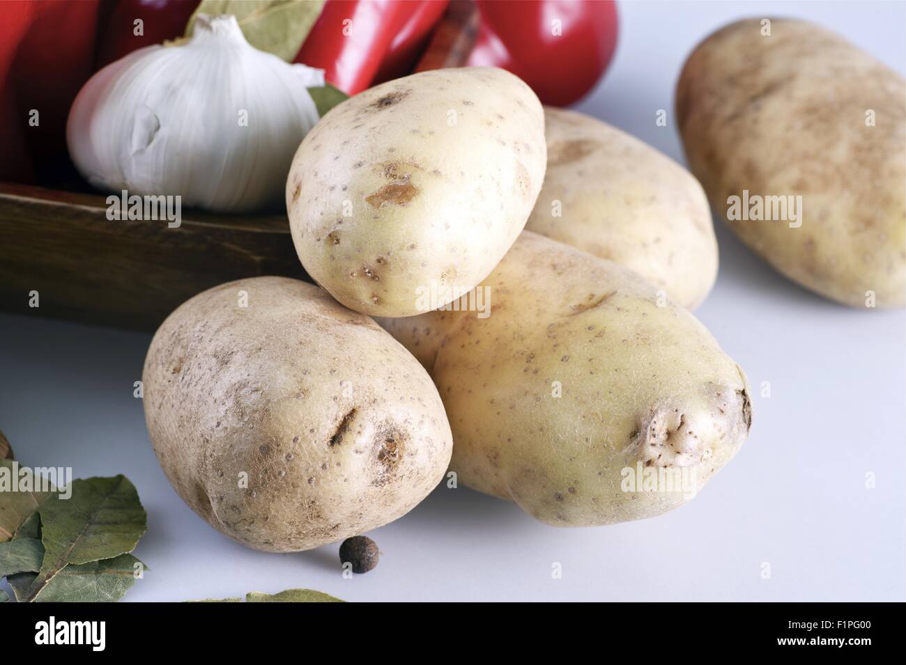 Bio-rohe Kartoffeln auf weißen Tisch mit anderen Gemüse im Hintergrund. Kartoffeln horizontale Foto. Stockfoto