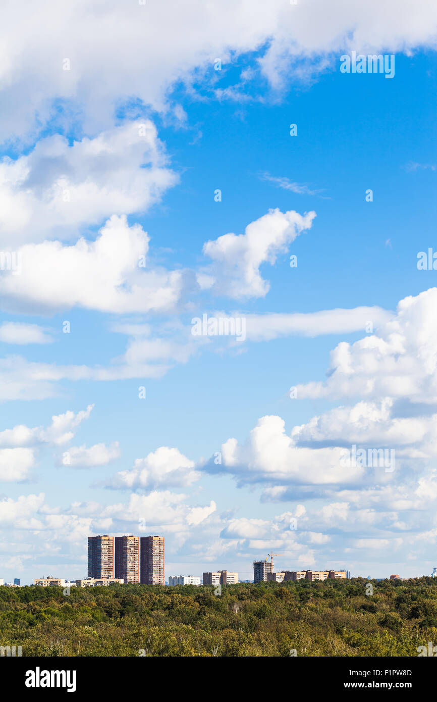 blauer Himmel mit weißen Wolken über städtische Gebäude und grünen Wald im Sommer Stockfoto