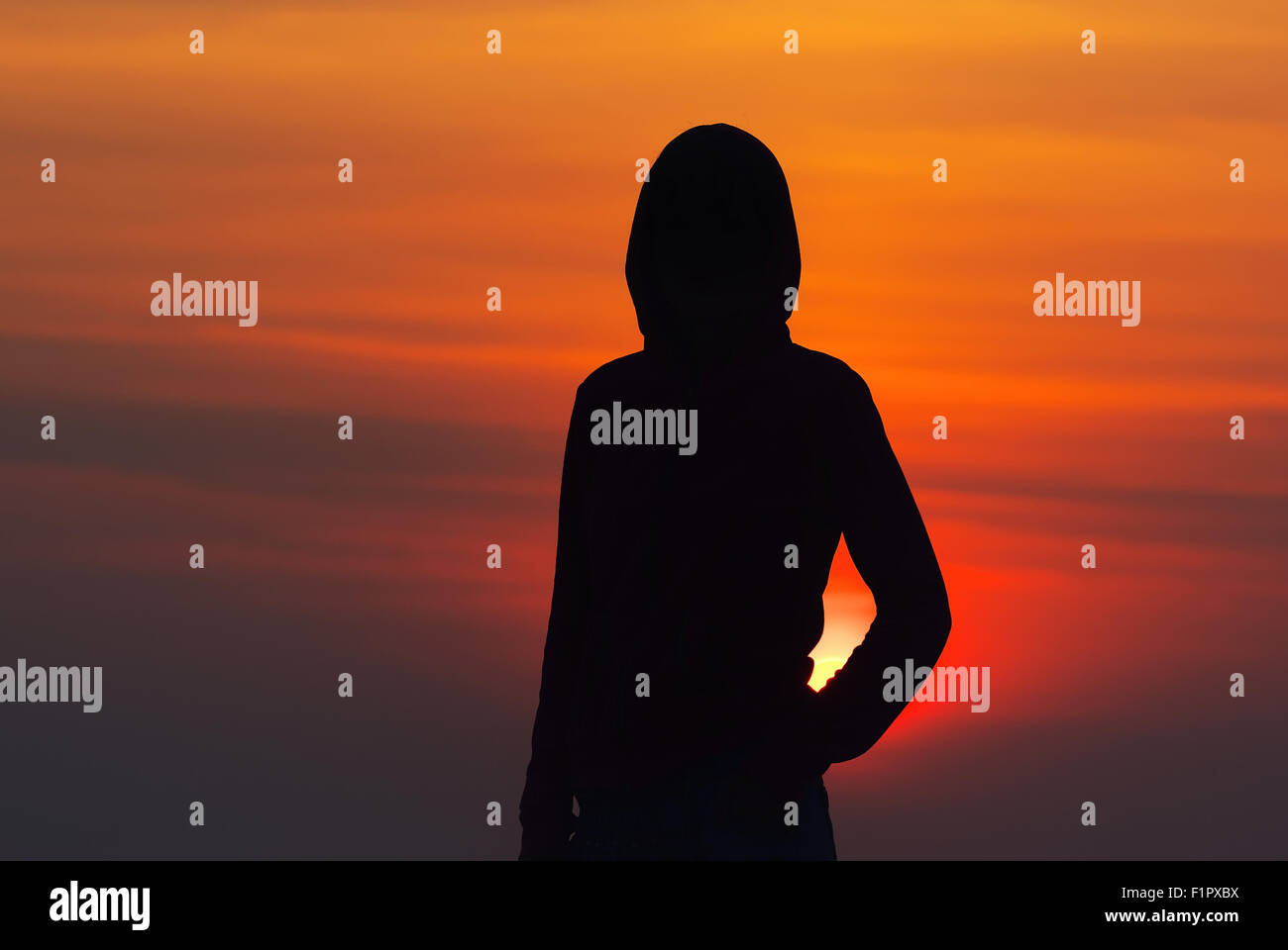 Silhouette des Mädchens in der Sportswear mit einer Haube bei Sonnenuntergang Stockfoto