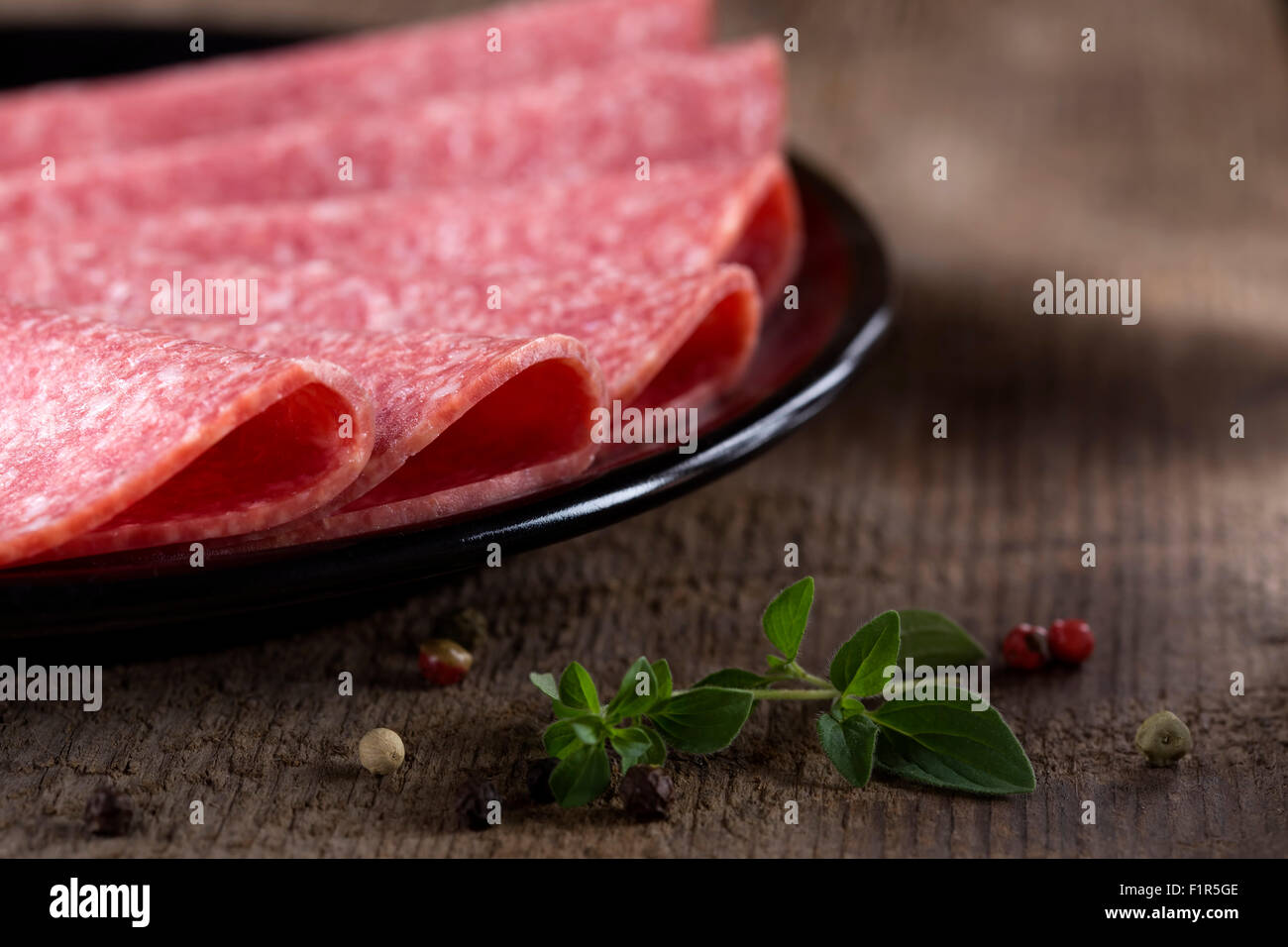 Salami auf schwarzen Druckplatte über hölzerne rustikalen Hintergrund Stockfoto