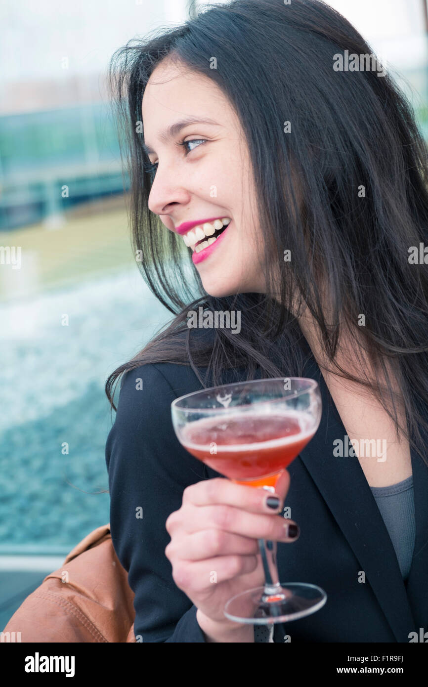 Junge lateinamerikanische/Latin Geschäftsfrau mit einem Mobiltelefon und einem cocktail drink Stockfoto