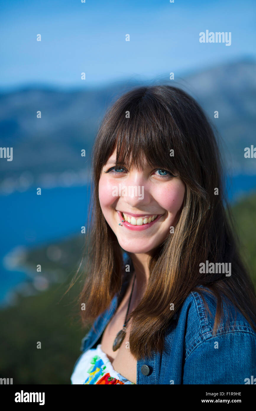 Eine attraktive junge Brünette Frau lächelt. Natürlicher Hintergrund Stockfoto