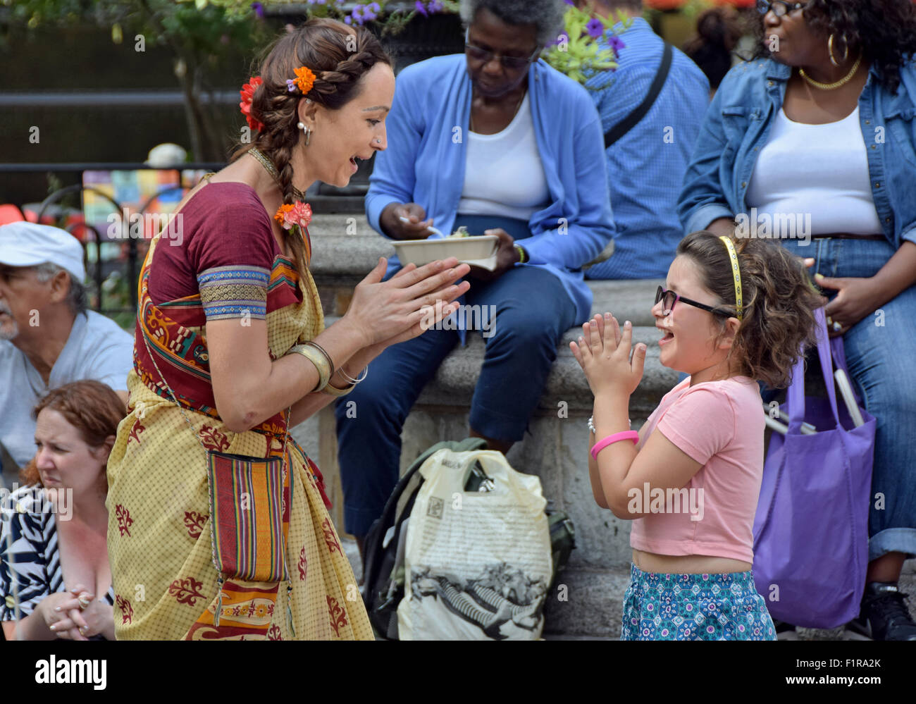 Ein lettischer Hare-Krishna-Anhänger spielt Patty Cake mit der Tochter ein Passant Freilos in Union Square Park in New York City Stockfoto