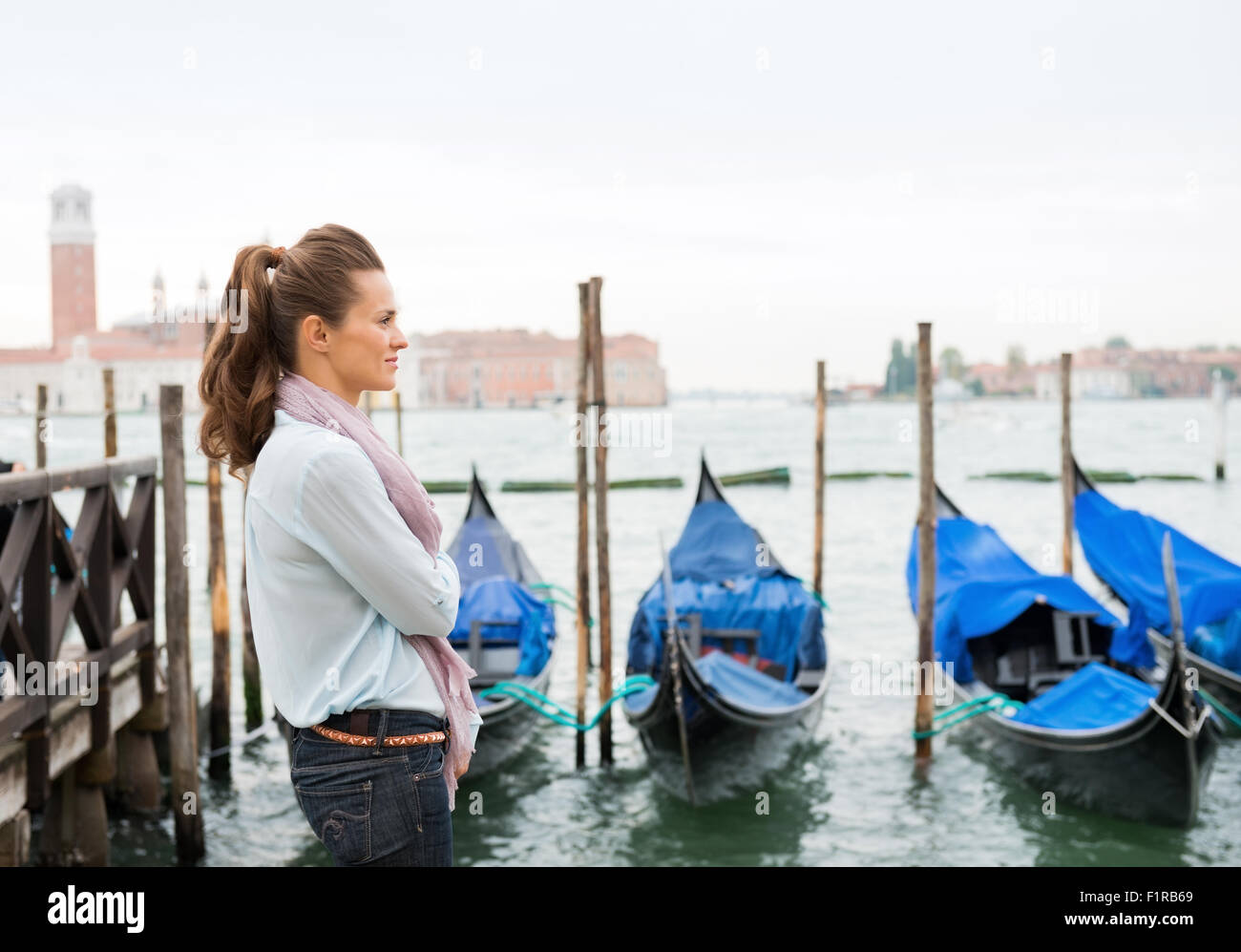 Eine Frau steht, Träumen der Vergangenheit hören auf den Klang des Wassers gegen die festgemachten Gondeln Läppen. Stockfoto