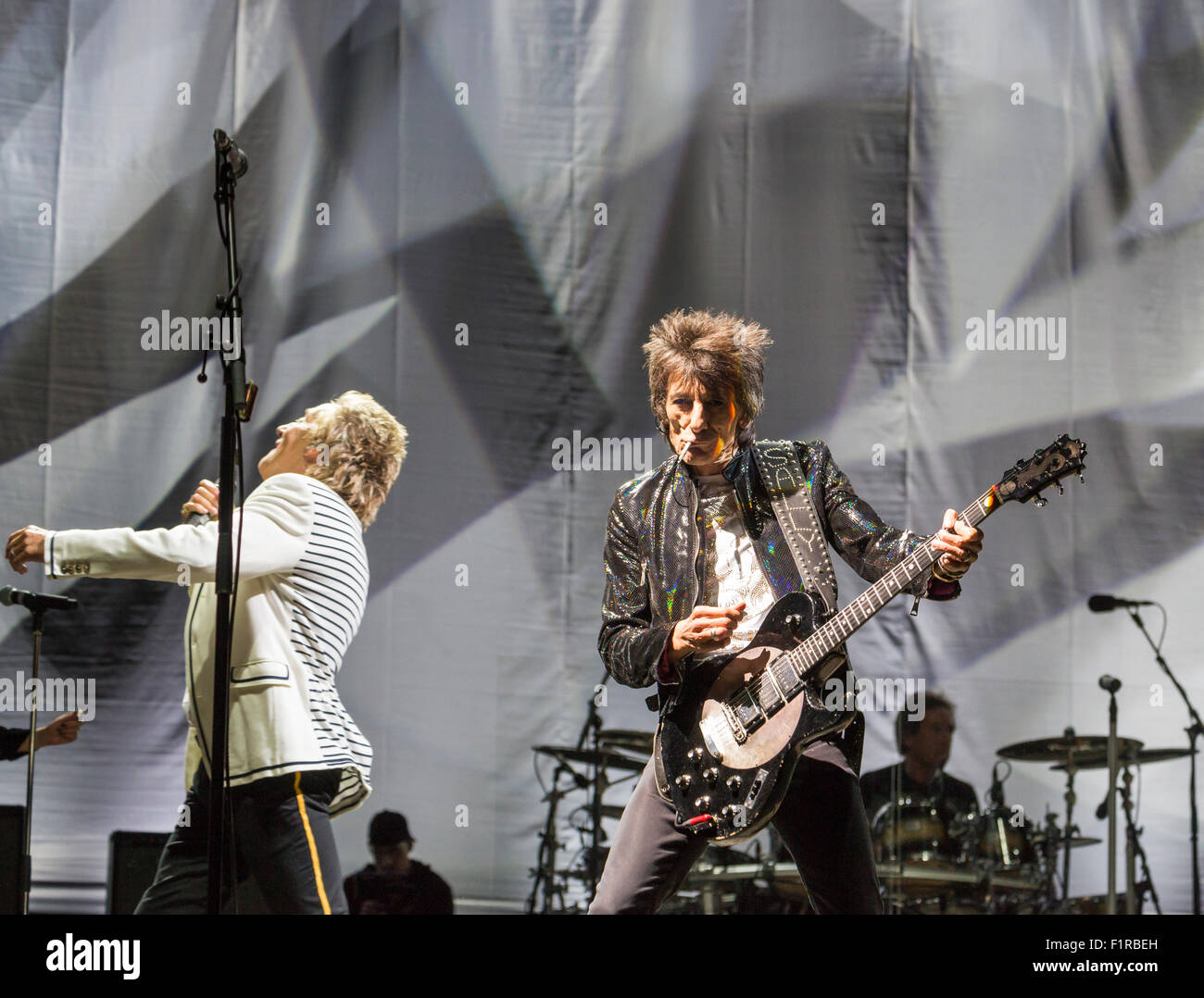 Ewhurst, Surrey, England.  5. September 2015.  Ronnie Wood raucht eine Zigarette, während die live auf der Bühne, wie er die Gitarre, Rod Stewart im Hintergrund spielt.  Die Gesichter Wiedersehen: Rod Stewart, Ronnie Wood und Kenney Jones, die überlebenden Mitglieder der The Faces durchgeführt zusammen zum ersten Mal in mehr als 40 Jahren in einem live-Konzert am Hurtwood Park Polo Club, Ewhurst, Surrey, England, als Teil des Felsens ' n ' PS-Veranstaltung zur Unterstützung der Prostate Cancer UK. Bildnachweis: Graham Lehrling/Alamy Live-Nachrichten Stockfoto