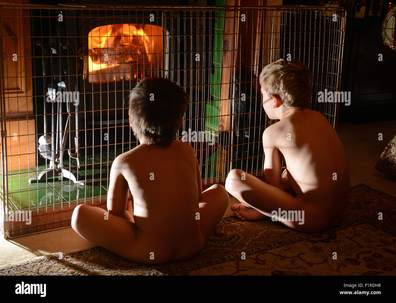 Kinder sitzen Warm halten von home Log Holzofen Feuer Uk Stockfoto