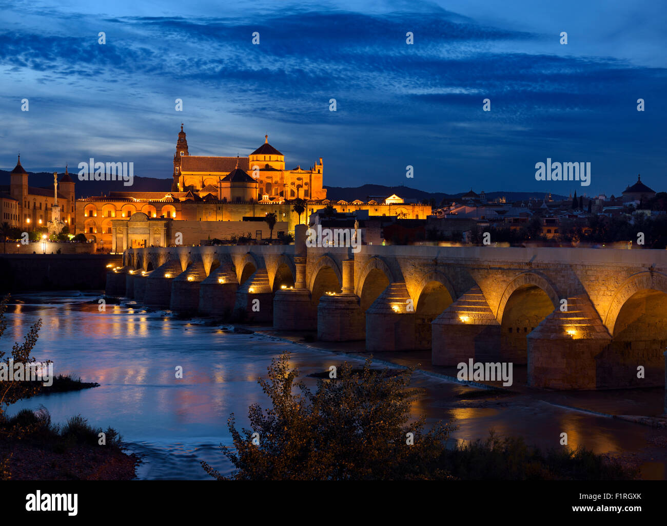 Römische Brücke über den Guadalquivir Fluss mit Bischofspalast und Cordoba Kathedrale in der Abenddämmerung Stockfoto